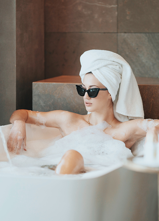 a women in a bath with her hair up and wearing sunglasses